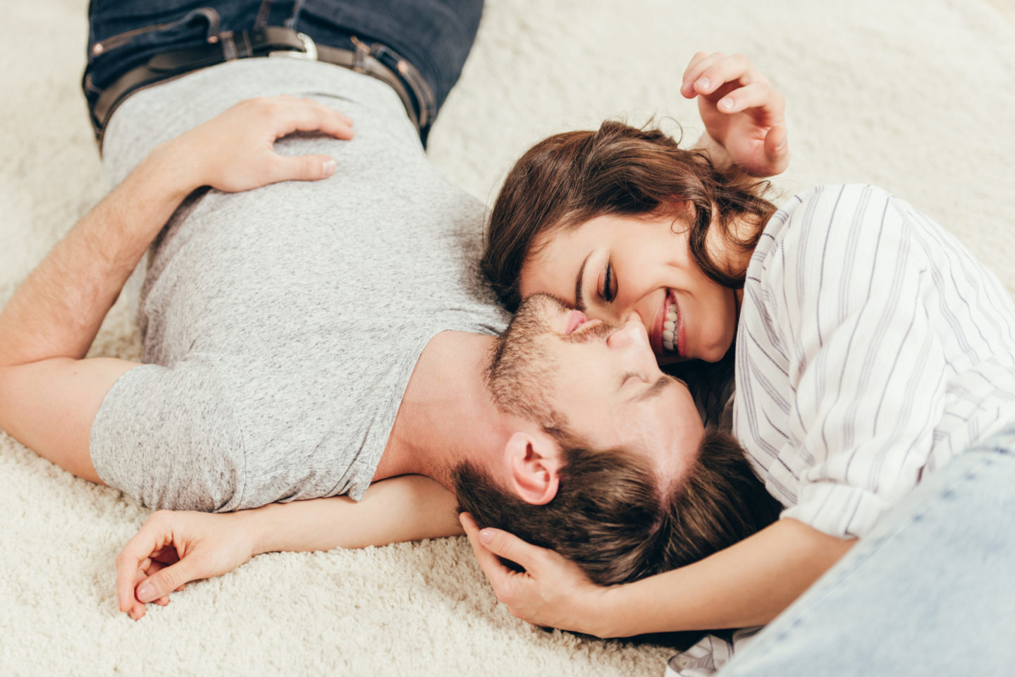 Ein Paar liegt entspannt auf dem Boden und lächelt sich an, was die enge Verbindung zwischen Darm und Psyche symbolisiert. Diese Beziehung wird oft durch die Bedeutung der Darmflora in der emotionalen Gesundheit hervorgehoben.