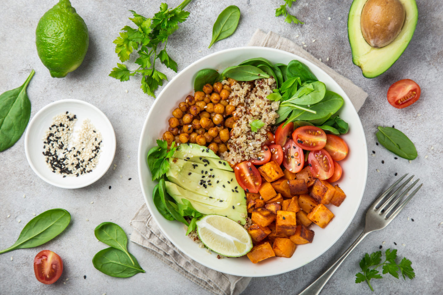 Buntes veganes Gericht mit Quinoa, Kichererbsen, Süßkartoffeln, Avocado, Spinat und Kirschtomaten, um Vitaminmangel in der veganen Ernährung zu vermeiden.