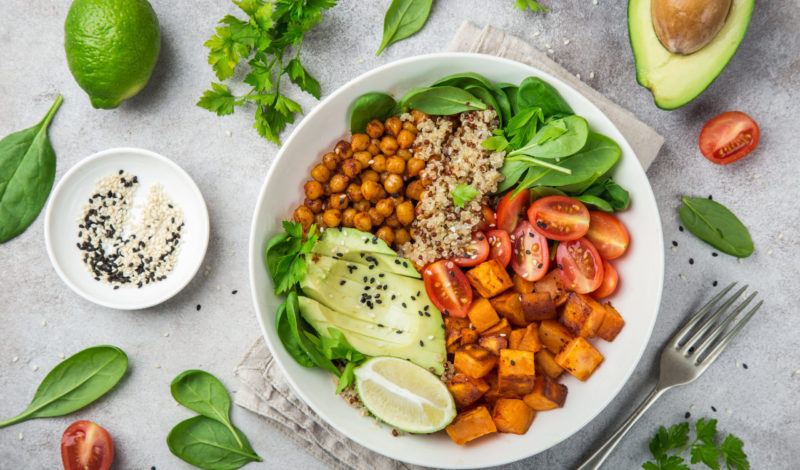 Buntes veganes Gericht mit Quinoa, Kichererbsen, Süßkartoffeln, Avocado, Spinat und Kirschtomaten, um Vitaminmangel in der veganen Ernährung zu vermeiden.