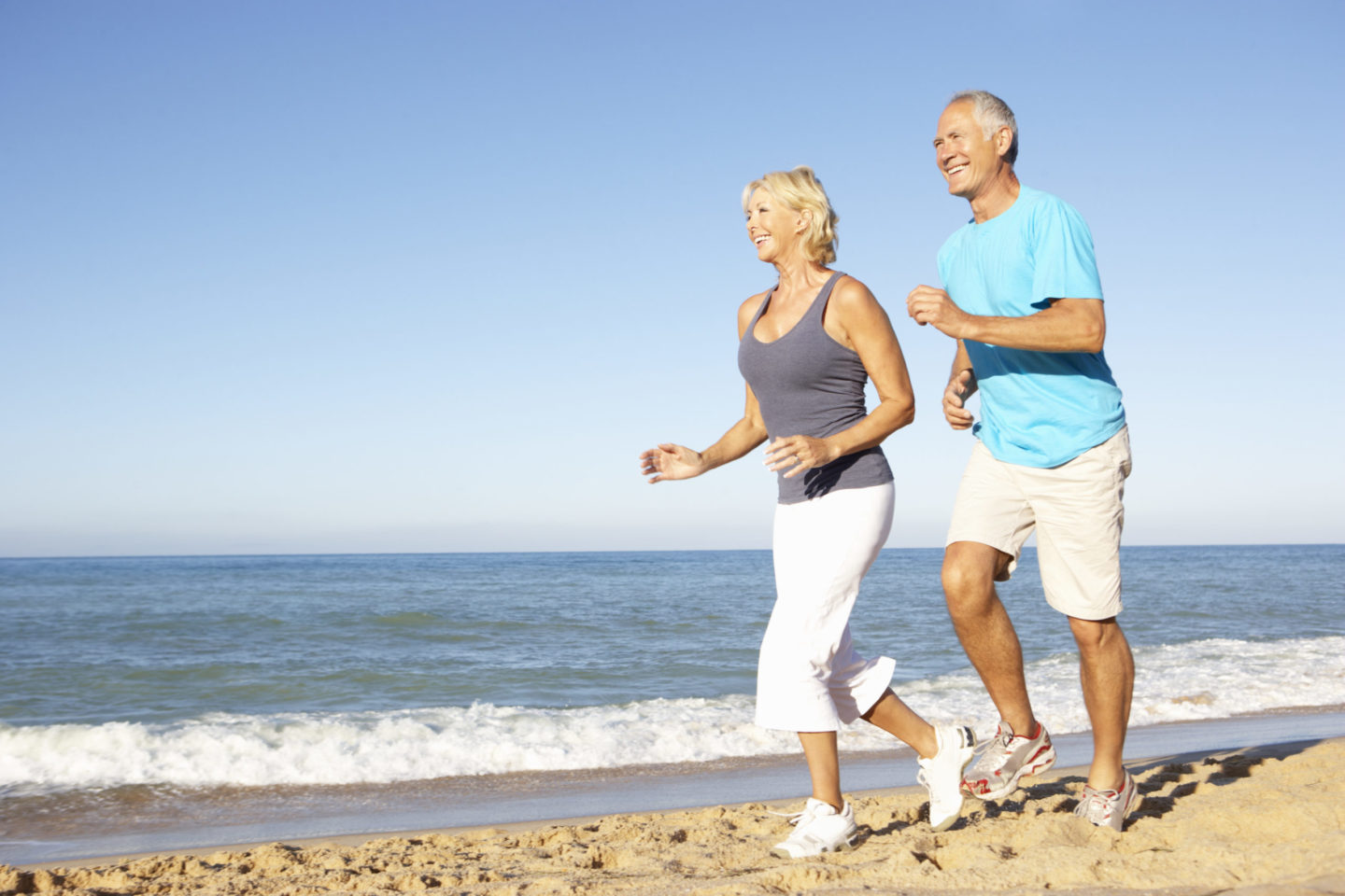 Aktives Paar mittleren Alters joggt am Strand, genießt Bewegung und gesunde Lebensweise zur Unterstützung des Muskelaufbaus im Alter.
