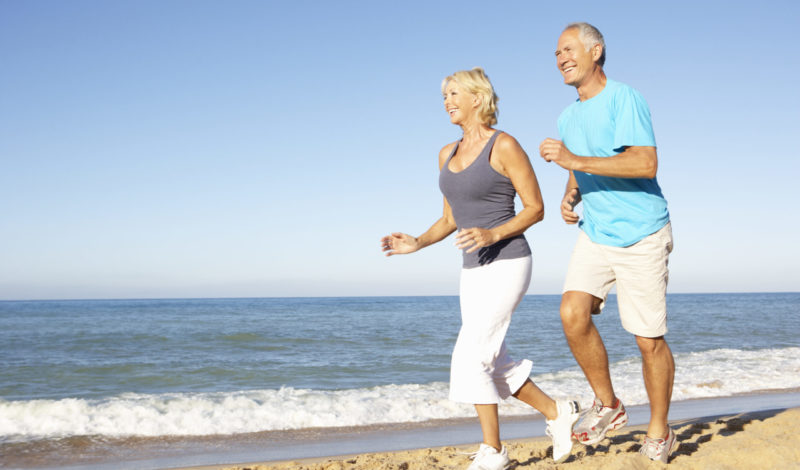 Aktives Paar mittleren Alters joggt am Strand, genießt Bewegung und gesunde Lebensweise zur Unterstützung des Muskelaufbaus im Alter.