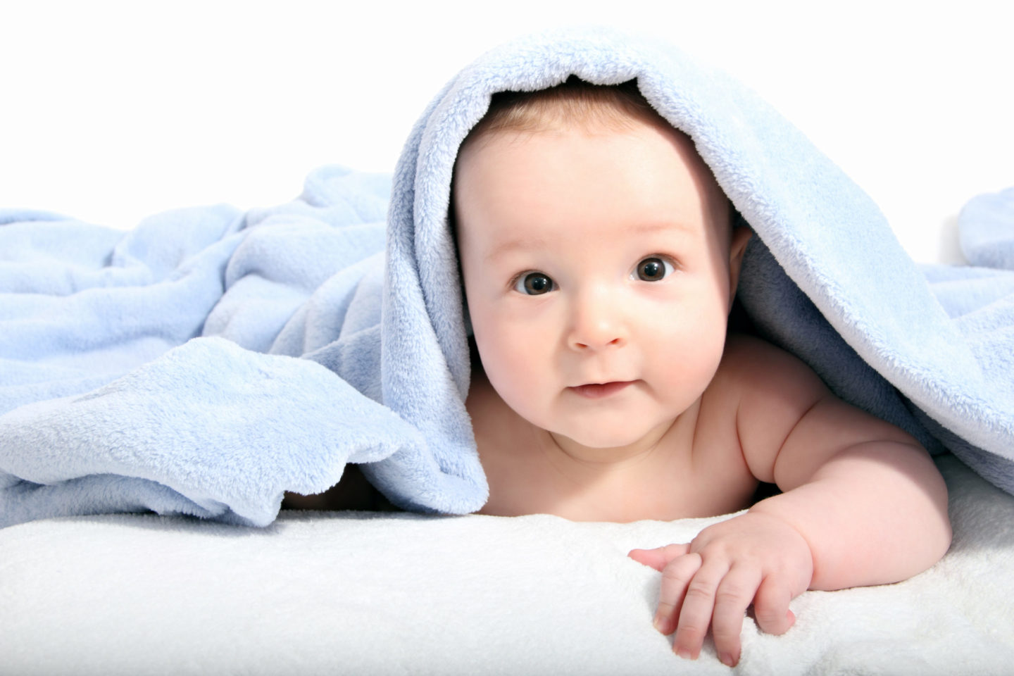 Neugeborenes Baby mit blauer Decke, das neugierig in die Kamera schaut. Tipps zur Stärkung des Immunsystems bei Neugeborenen werden in diesem Artikel behandelt.